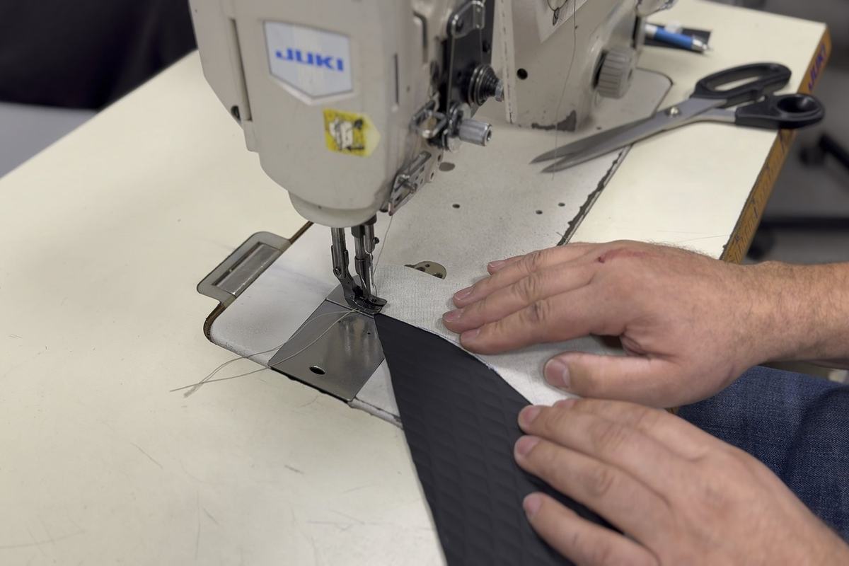 Hands guiding leather through the sewing machine